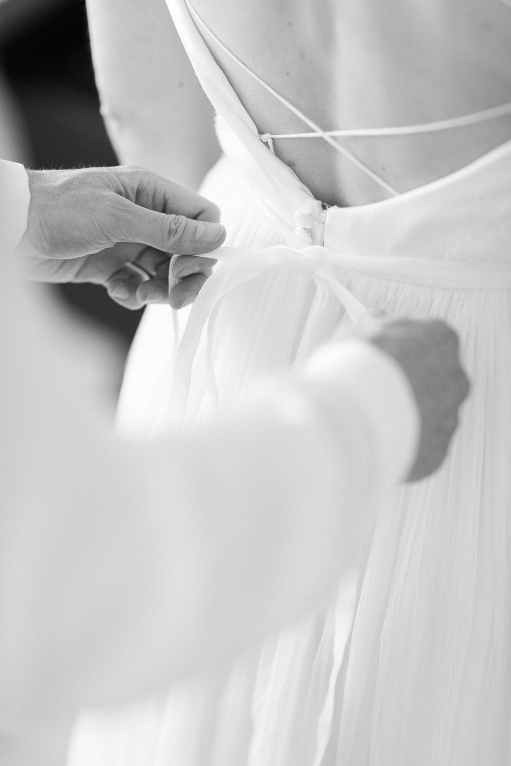 Bräutigam hilft der Braut beim Anziehen des Hochzeitskleides (Hochzeitsreportage in Luzern)