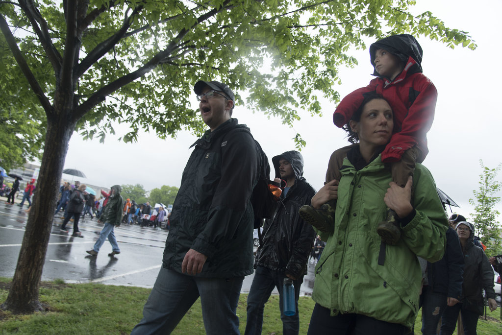 A woman carries her son on her shoulders as they march towards to Capitol during the March for Science in Washington DC on April 22, 2017. 