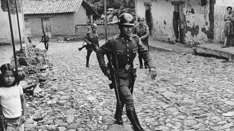 Armed soldeirs walk through a Salvadoran village in the 1980s / Photo Al Jazeera