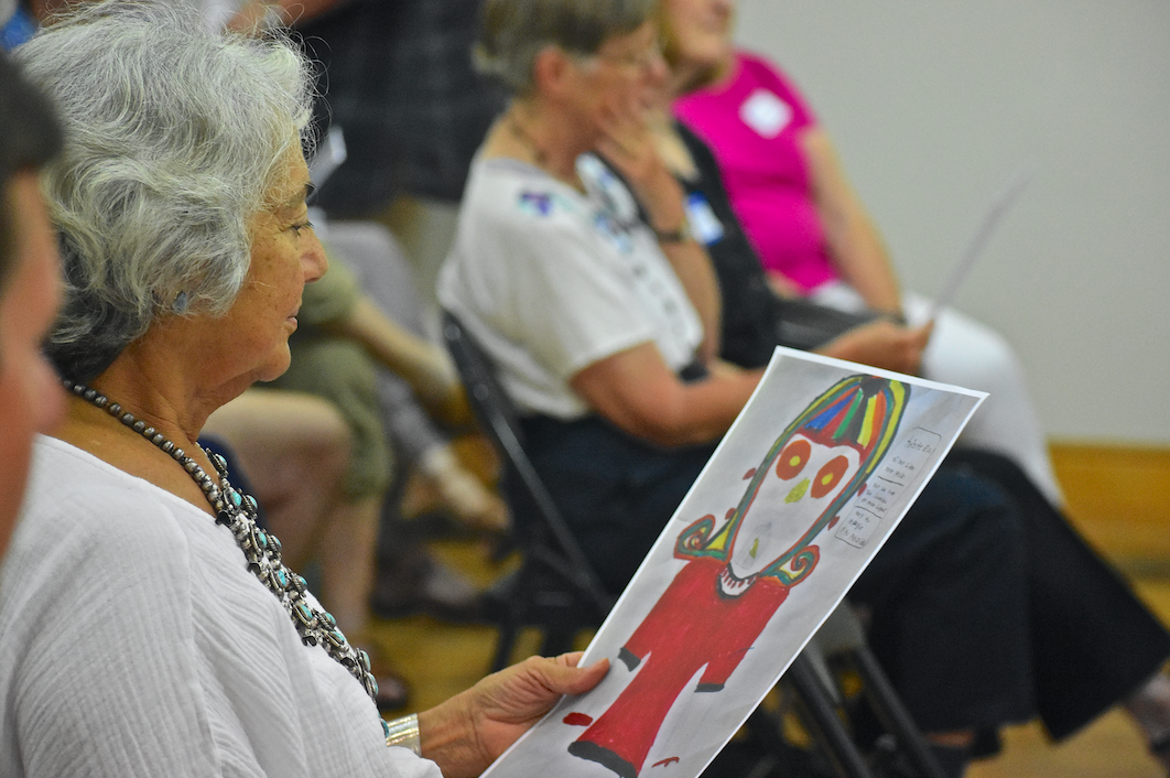 An All Saints' event attendee examines a drawing and poem created by a girl in Cristosal's protection program
