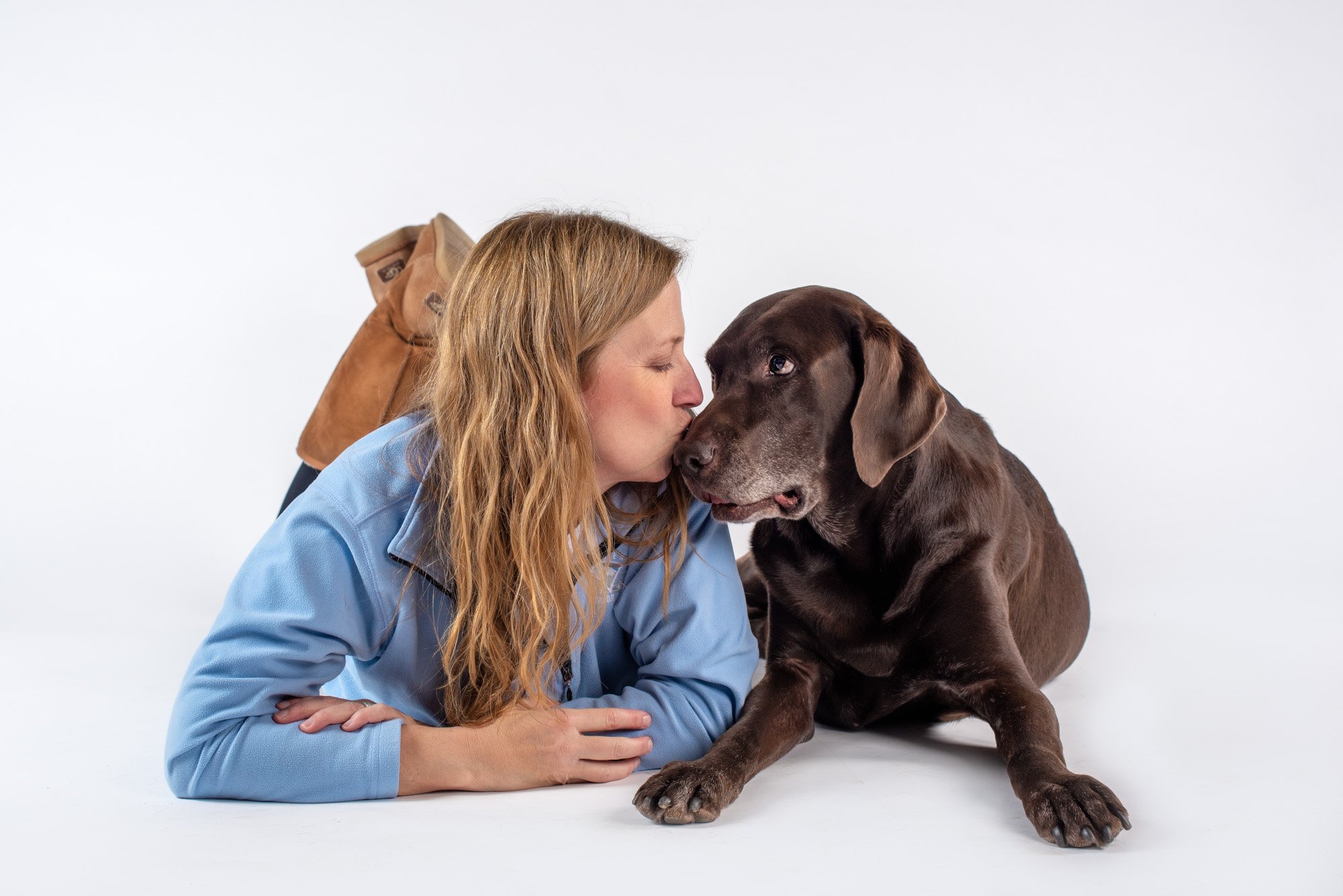 dog mom kissing chocolate lab's nose