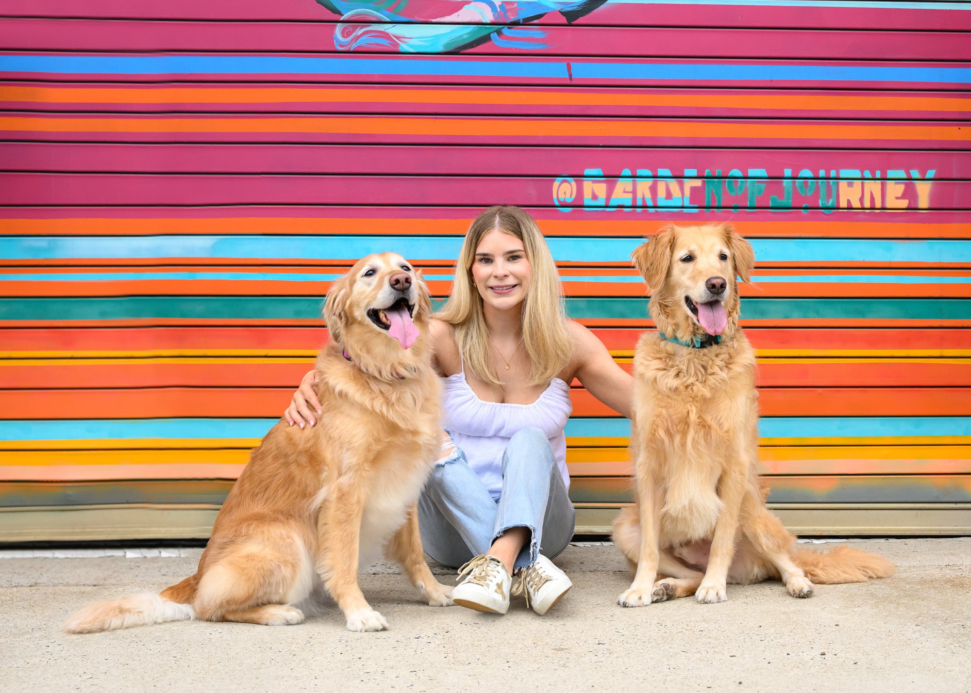 dog mom with 2 golden retrievers in front of colorful mural