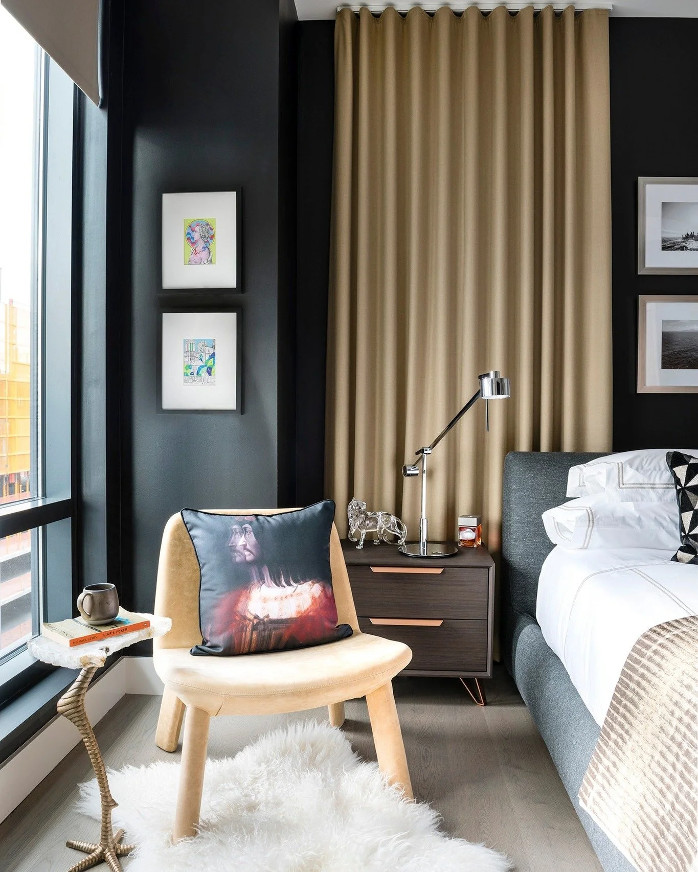 A study in contrast and calm. This primary bedroom layers tone-on-tone neutrals with sleek black walls and tailored drapery to create depth without distraction. Thoughtful art, sculptural lighting, and soft texture make it equal parts modern and invi