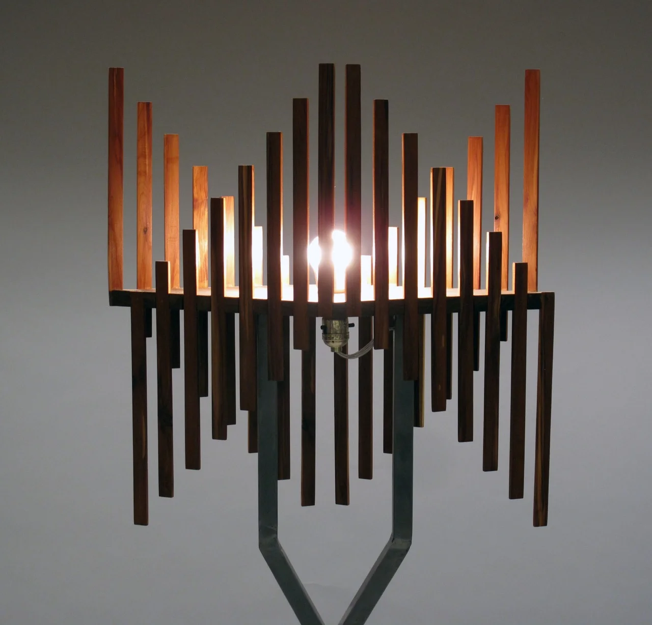  slats of spanish cedar arpeggiate across the bulb, framing and diluting light 