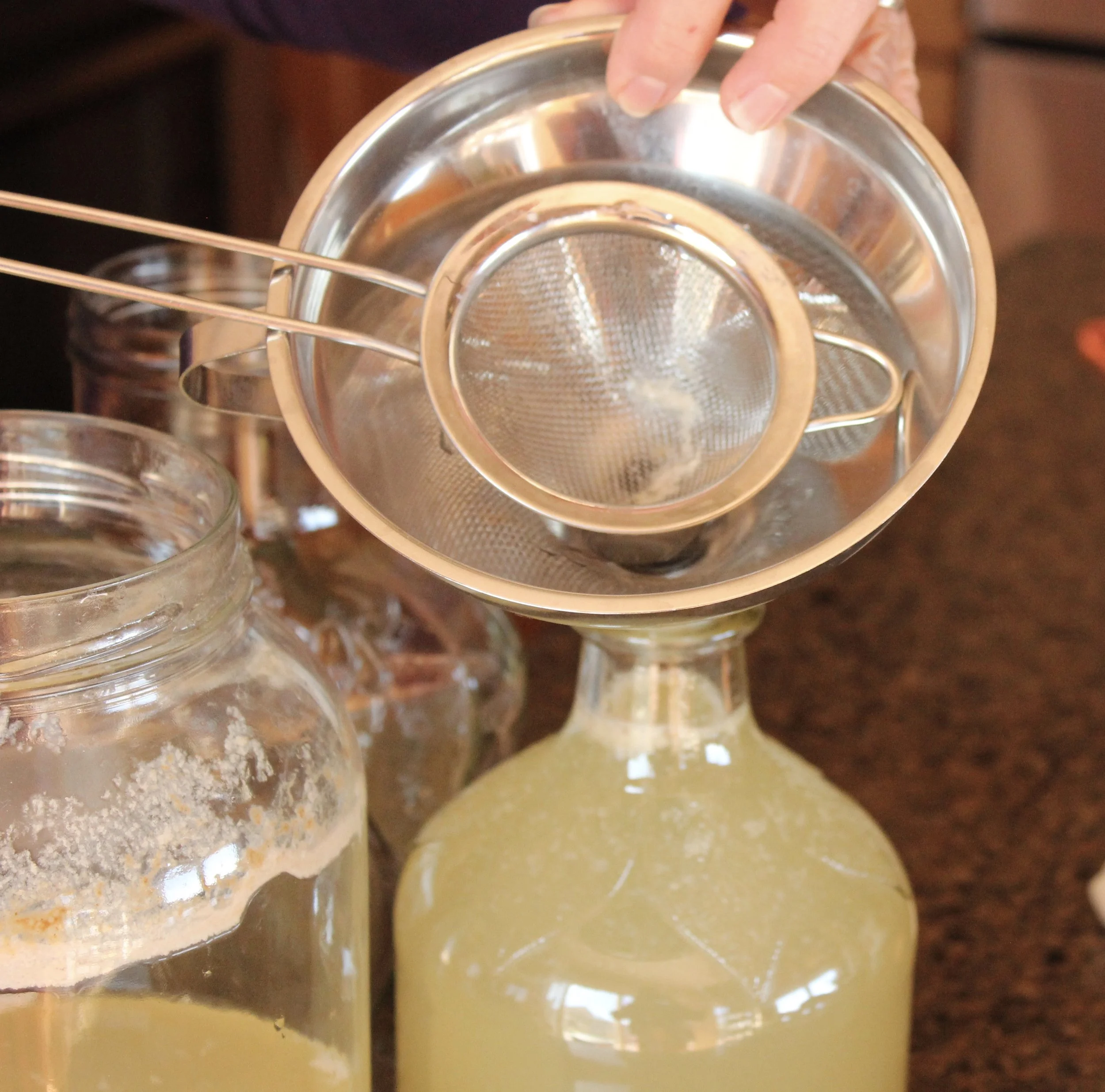Here is the set up I used to strain out most of the "mother." (The "mother" consists of the bacteria and yeasts that ferment the liquid.) It's basically a small strainer inside a larger funnel. If you really wanted a fine-strained liquid--I'd lay a few layers of cheesecloth over the stop of the strainer too. I want a little more fermentation, so I'm not worrying about it.
