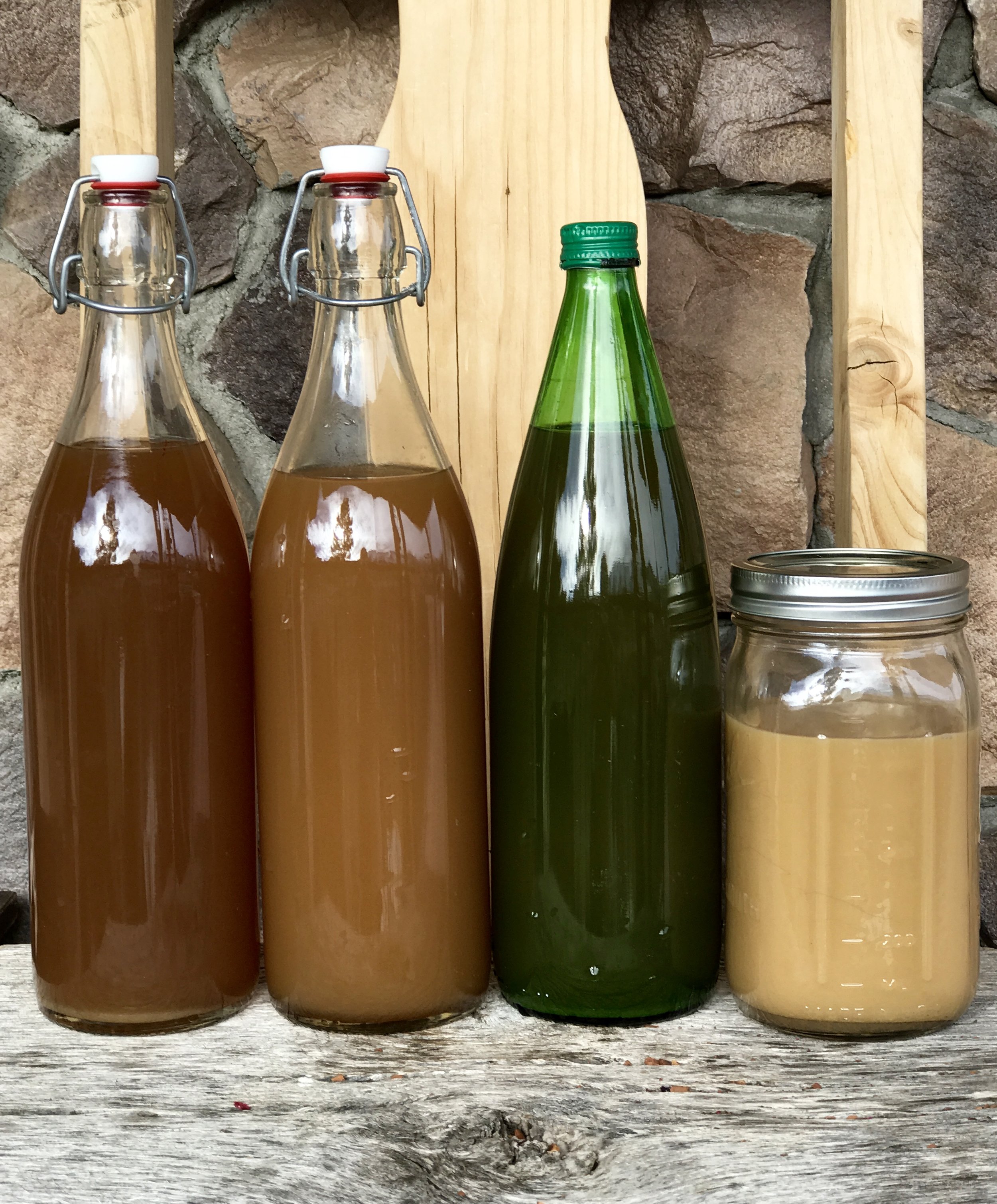 The two bottles on the left are swing top (Grolsch) bottles, both clear. The green bottle is a repurposed lemon juice bottle with a screw on lid (NOT recommended for making home brew), and finally, a Mason jar. The difference in colors of the brew i…