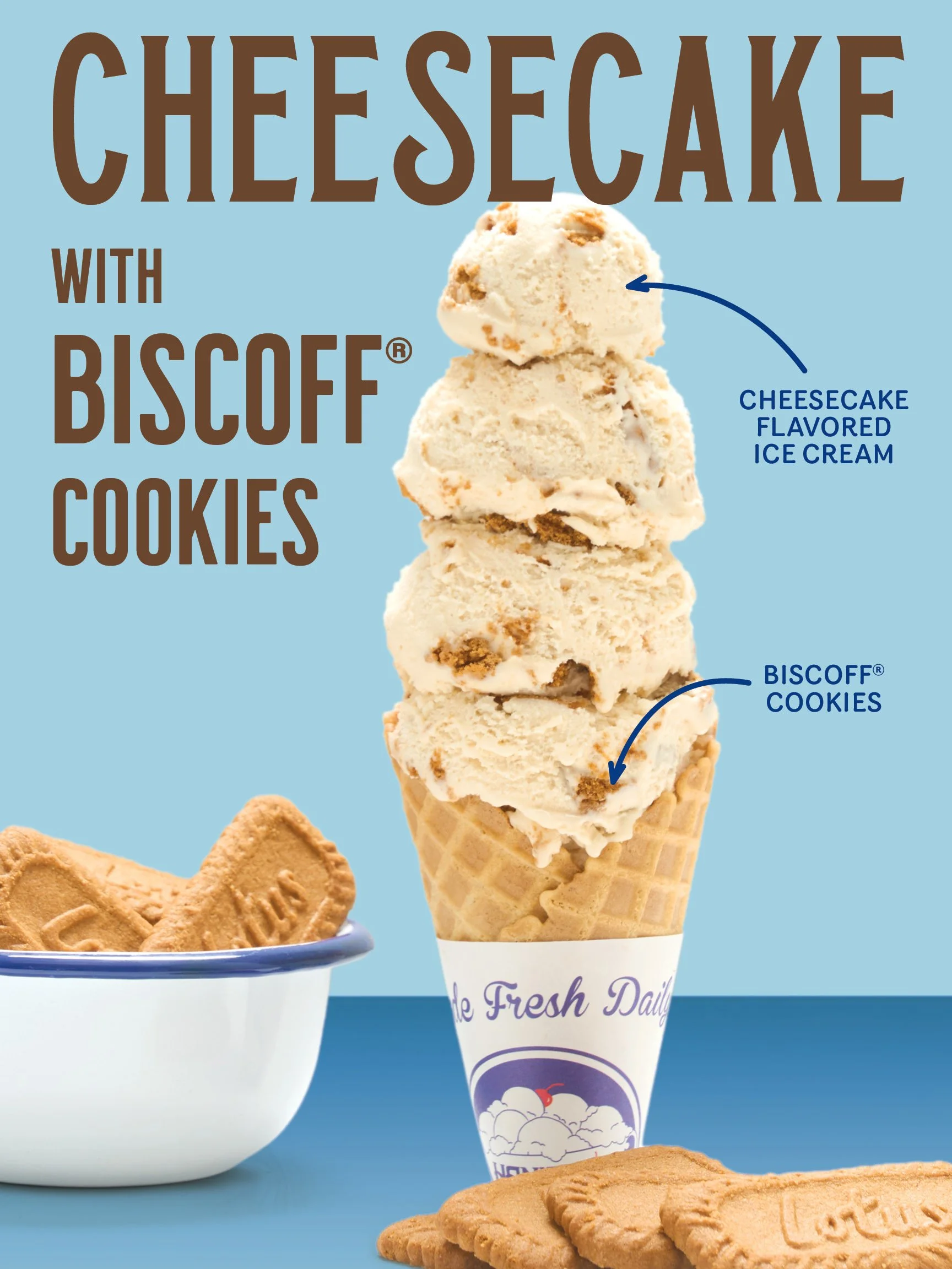 A scoop of cheesecake flavored ice cream with Biscoff cookies in a cone, with labels indicating cheesecake flavor and cookies, along with part of a plate of Biscoff cookies in the foreground.