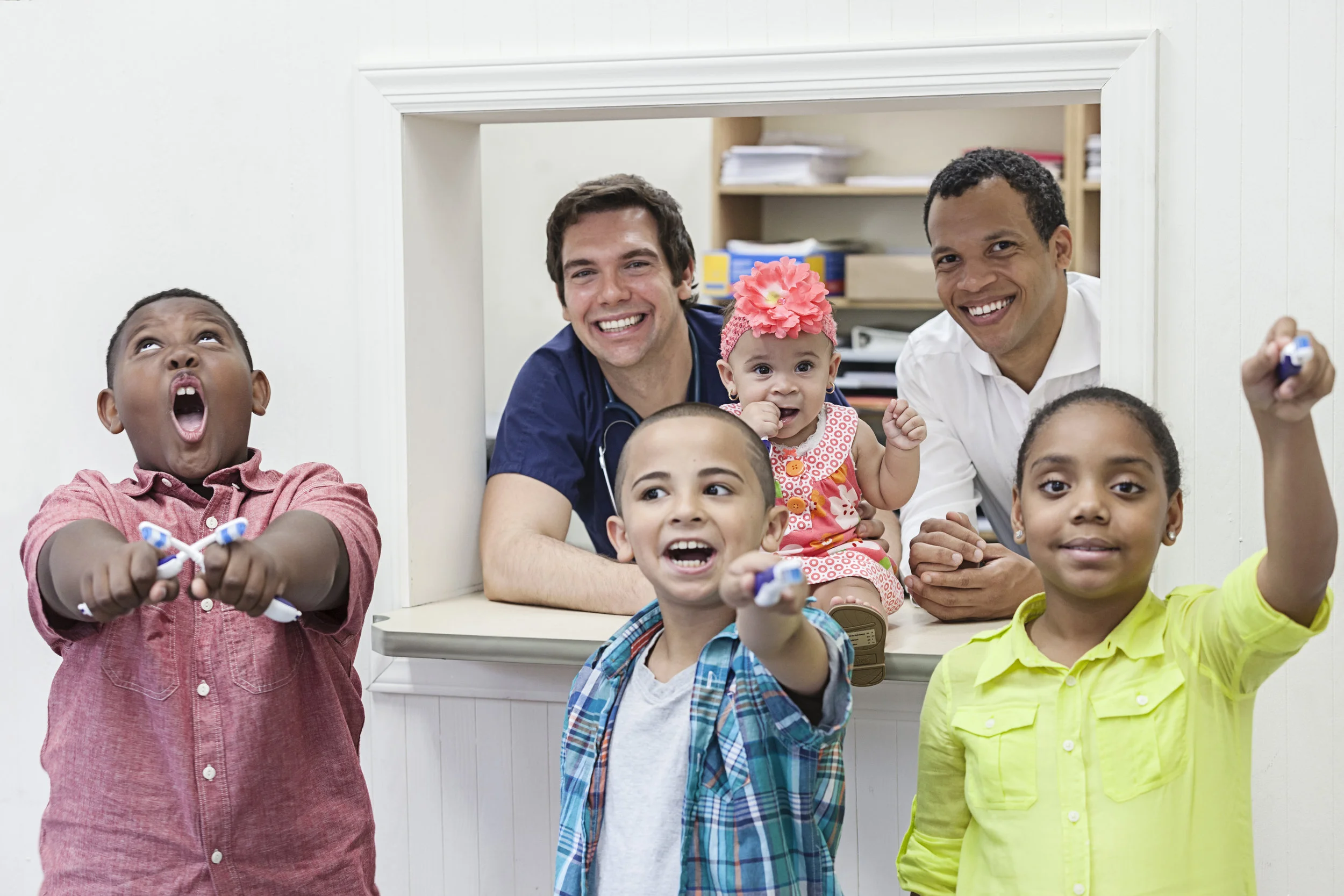 Kids holding toothbrushes with the dentist