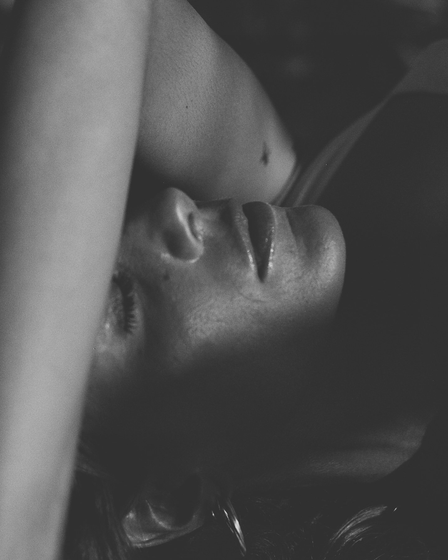 Close-up of a woman's face lying down, with her eyes closed, in black and white.