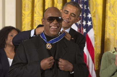 Photo by: Jacquelyn Martin Musician Stevie Wonder celebrates as President Barack Obama awards him the Presidential Medal of Freedom, Monday, Nov. 24, 2014, during a ceremony in the East Room of the White House in Washington. President Obama is presenting the nation's highest civilian honor to 19 artists, activists, public servants and others. (AP Photo/Jacquelyn Martin)