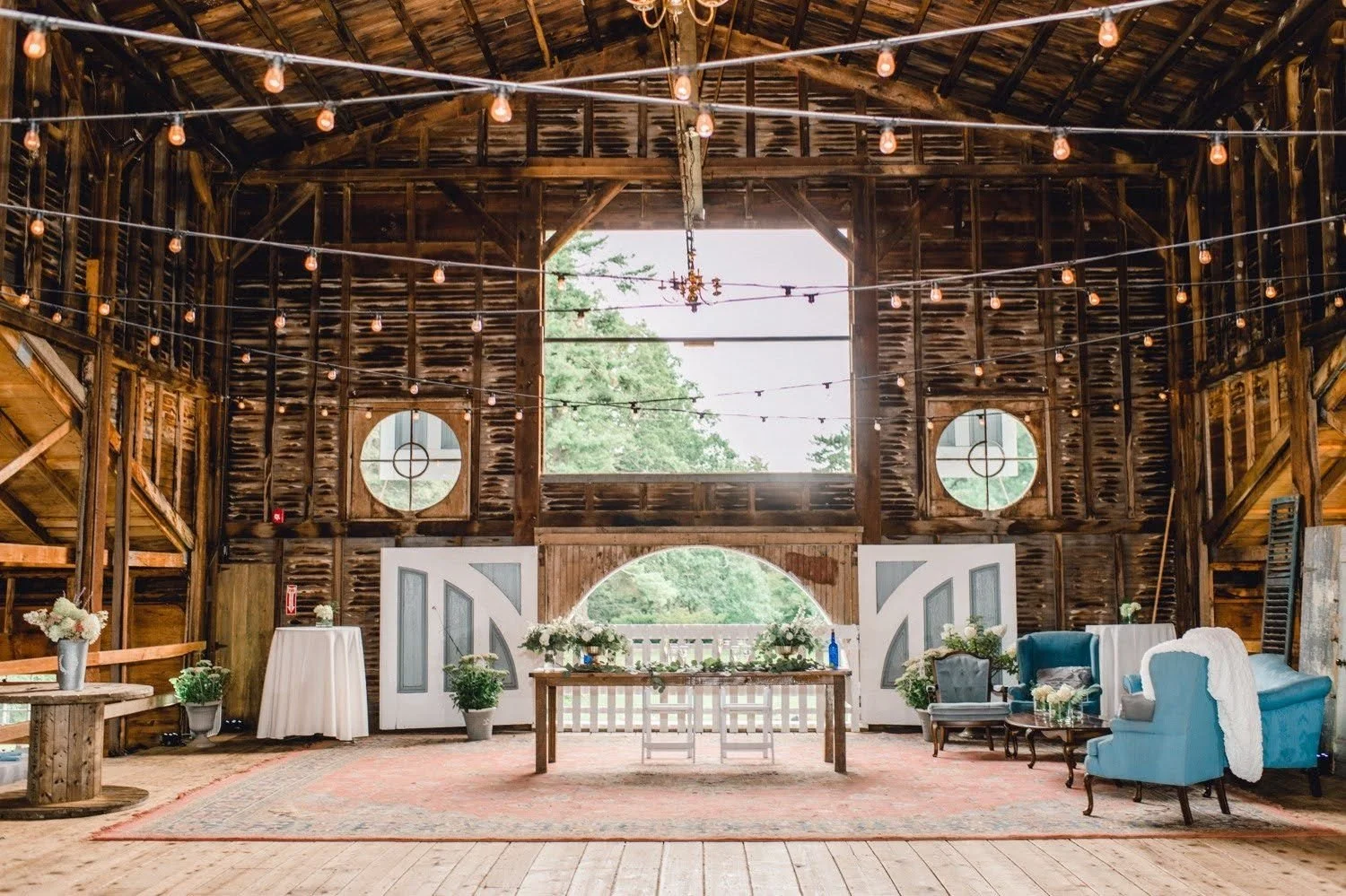 Blue and white furniture set up for wedding photos inside the Palladian Barn, a grand space with string lights