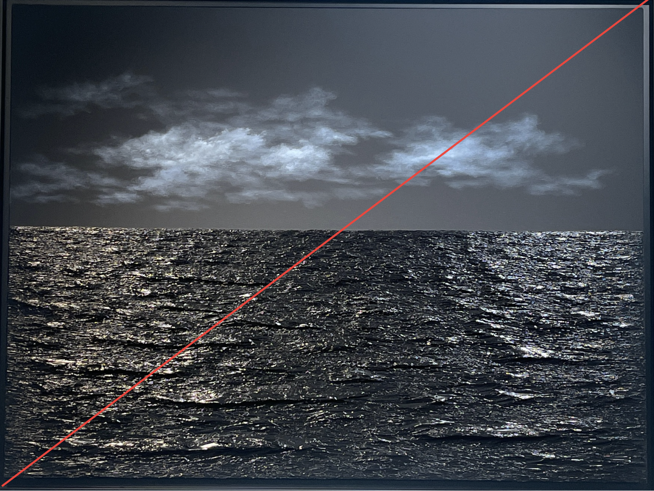 Une mer sombre avec des vagues réfléchissant la lumière. Au-dessus, un ciel nuageux avec des nuages gris et blancs.