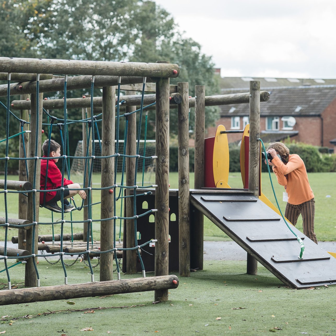 photographer taking school photo on climbing frame, UK school