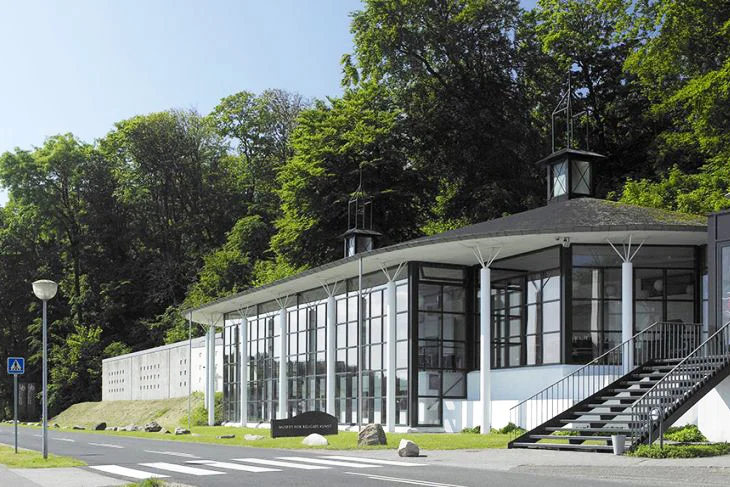 Museet for Religiøs Kunst "At der i dag ligger et kunstmuseum i Lemvig, der som sit særlige område har den religiøse kunst, udspringer af den store udsmykning af Lemvig kirke, som billedkunstneren Bodil Kaalund udførte 1976-81. Kunstnerens samarbejde med befolkningen på egnen førte til mange samtaler om kunstens væsen og om dens rolle og forhold til kirke og religion. De store eksistentielle spørgsmål om liv og død, om tilværelsens mening og sammenhæng optager mange mennesker. Den nye generation søger viden om vore kulturelle rødder. Samtidig har globaliseringen åbnet verden for alle, og forståelse samfundene imellem er blevet mere nødvendig end nogensinde. Kunsten har til alle tider tydet, hvad der rører sig i tiden. Derfor er det vigtigt, at den bliver vist." Adresse: Strandvejen 13, 7620 Lemvig. Links: Mfrk.dk Foto: Museet for Religiøs Kunst.
