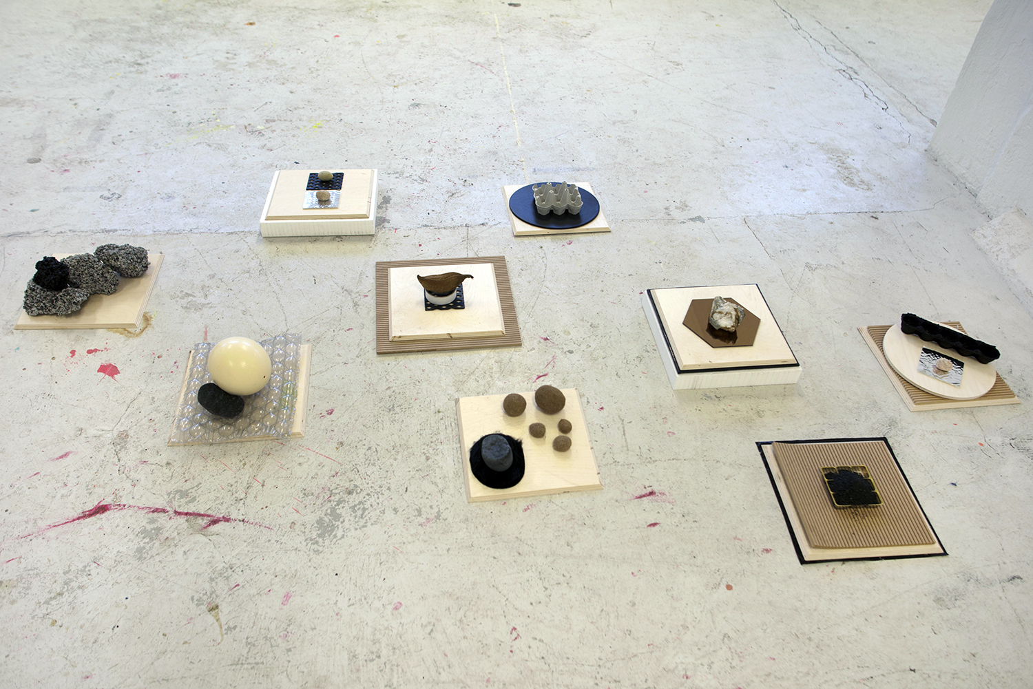 Mette Borup Kristensen, Uden titel (træ, sten, æggebakker, spejl, plastik, bobleplast, flamingo, strudseæg, glimmer, tekstil, sort sand, asfalt, organisk materiale).
