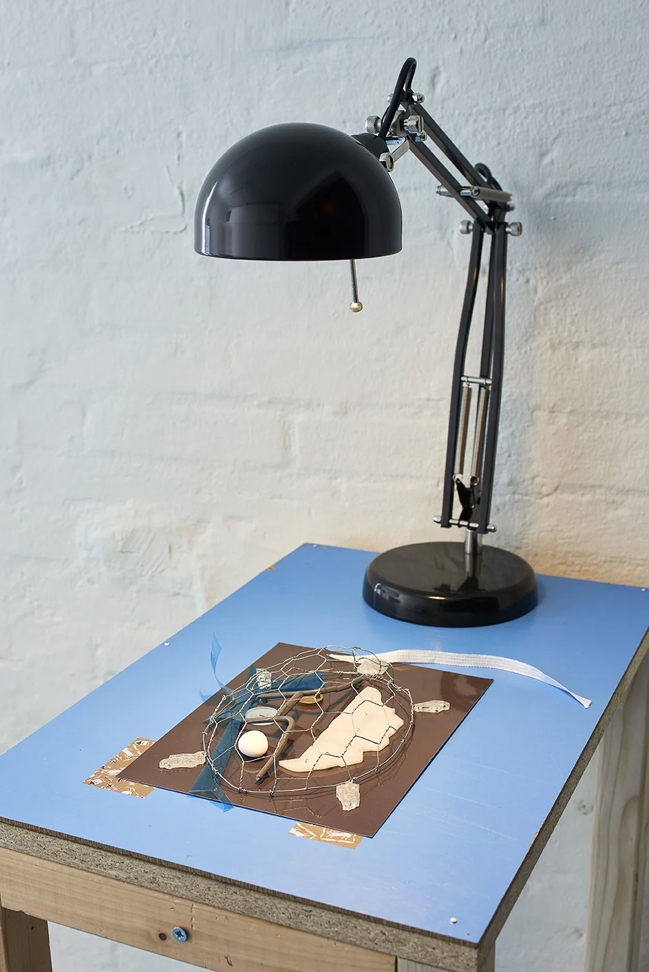 Kah Bee Chow âUden titel,â 2019 (chipboard, wood, laser-cut and engraved plexiglass coin, mint, lighting gel, glass, photo paper, washi tape, lamp, silicone, wire, screws, nails). Foto: Kirstine Mengel.