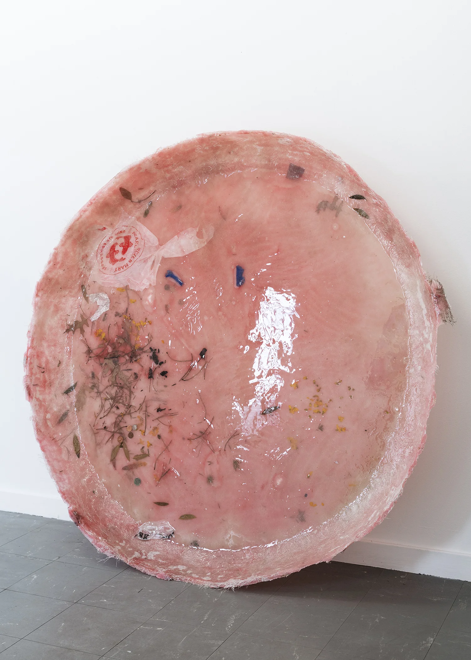 Cecilie Skov “Våd af dug,” 2019 (Epoxy-resin, glasfiber, plastik pose, blade, blomster, sugerør, salt, sukker, fennikel frø, sølvpapir, tape, voks, mønter, pigment. Ø: 130 cm). Foto: Karl Isaksen.