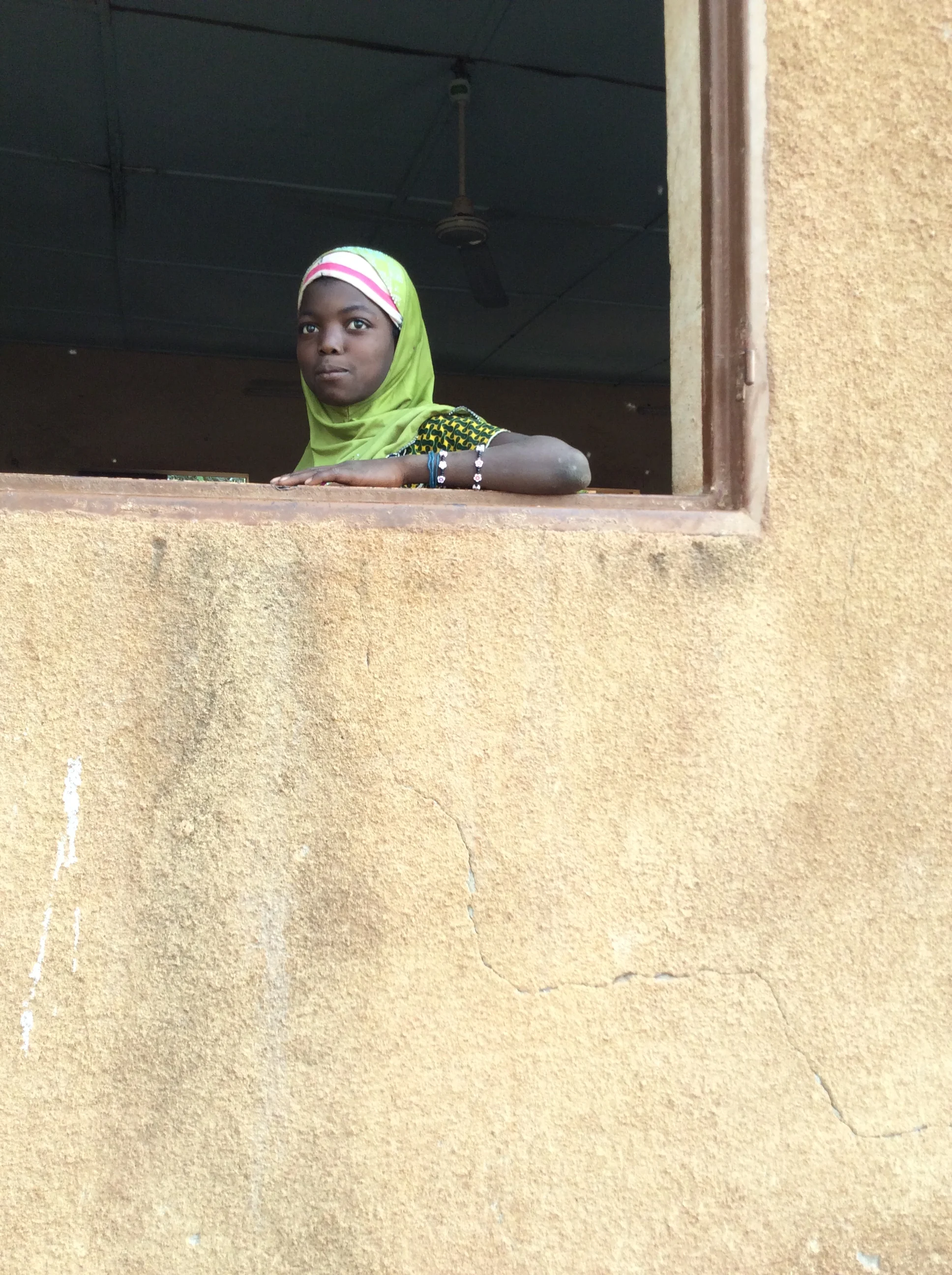 A young girl looks out the school window in our partner village, Beneko.