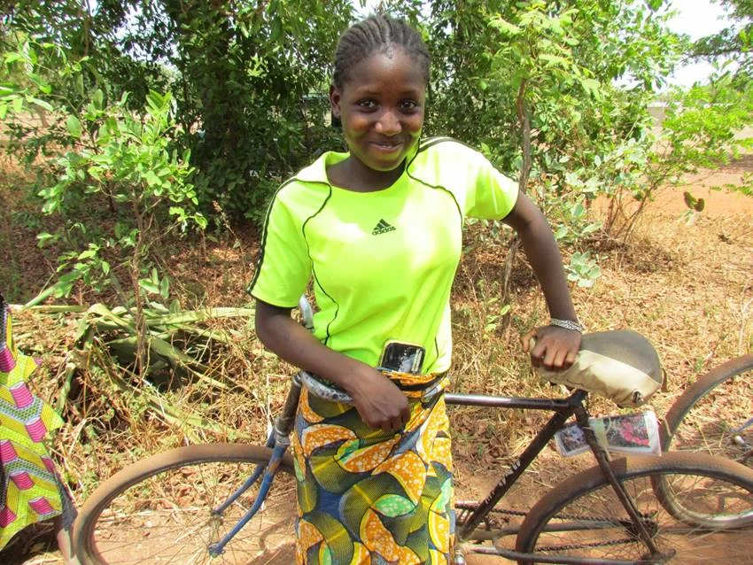 A bike is a hand tool for covering the long, dusty road to school for girls like Alima, who face long, hot trips on dusty roads.