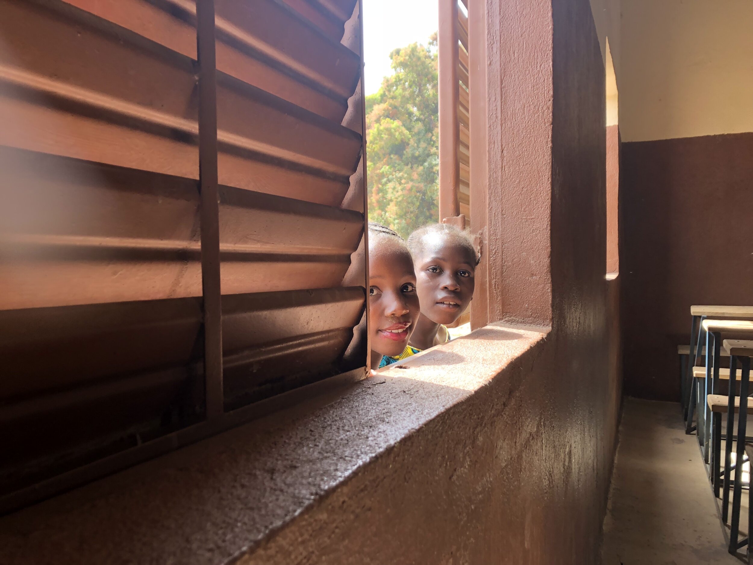 Young girls peek inside the school.