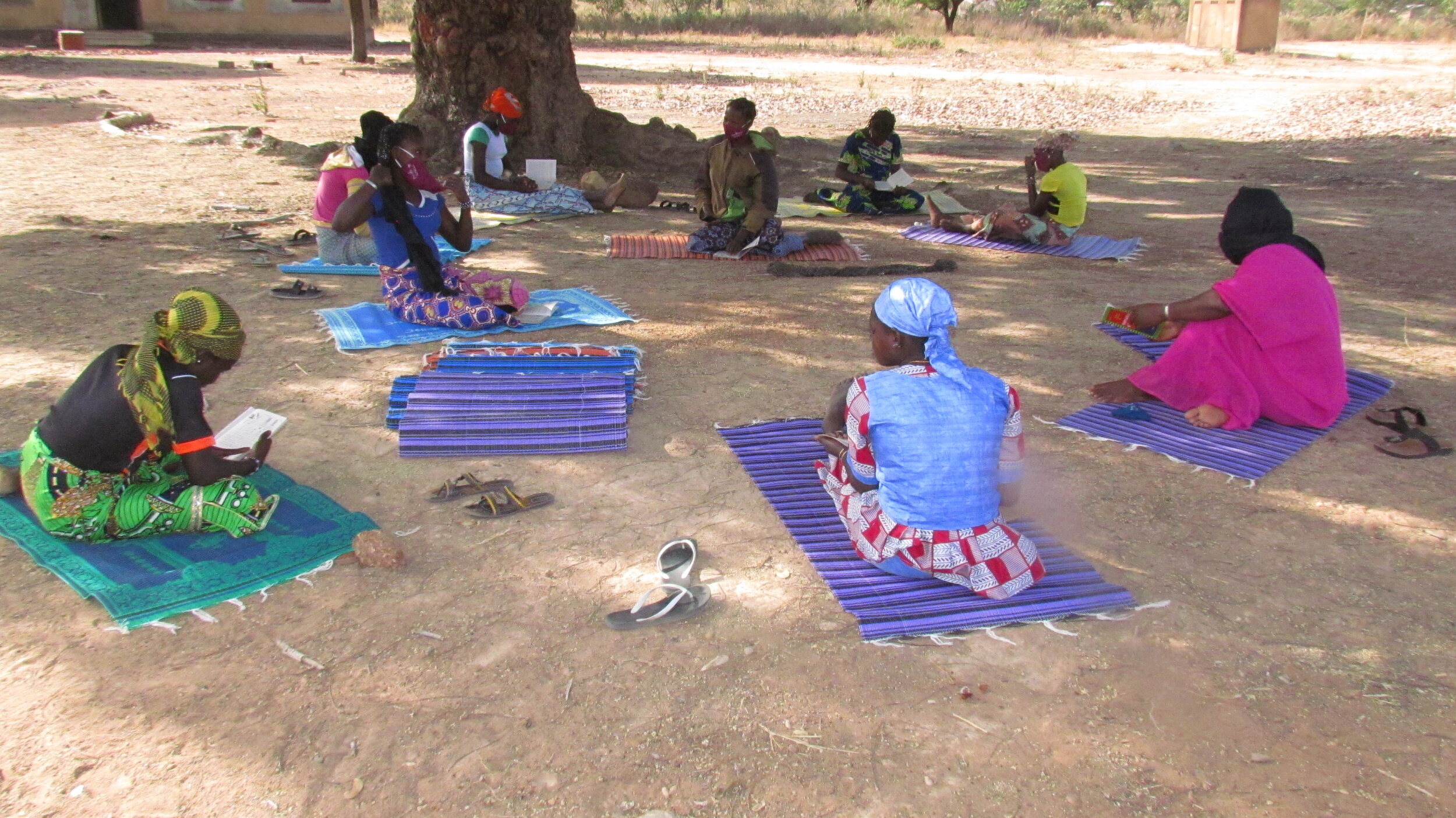 Girls gather under the trees with their reading primers.