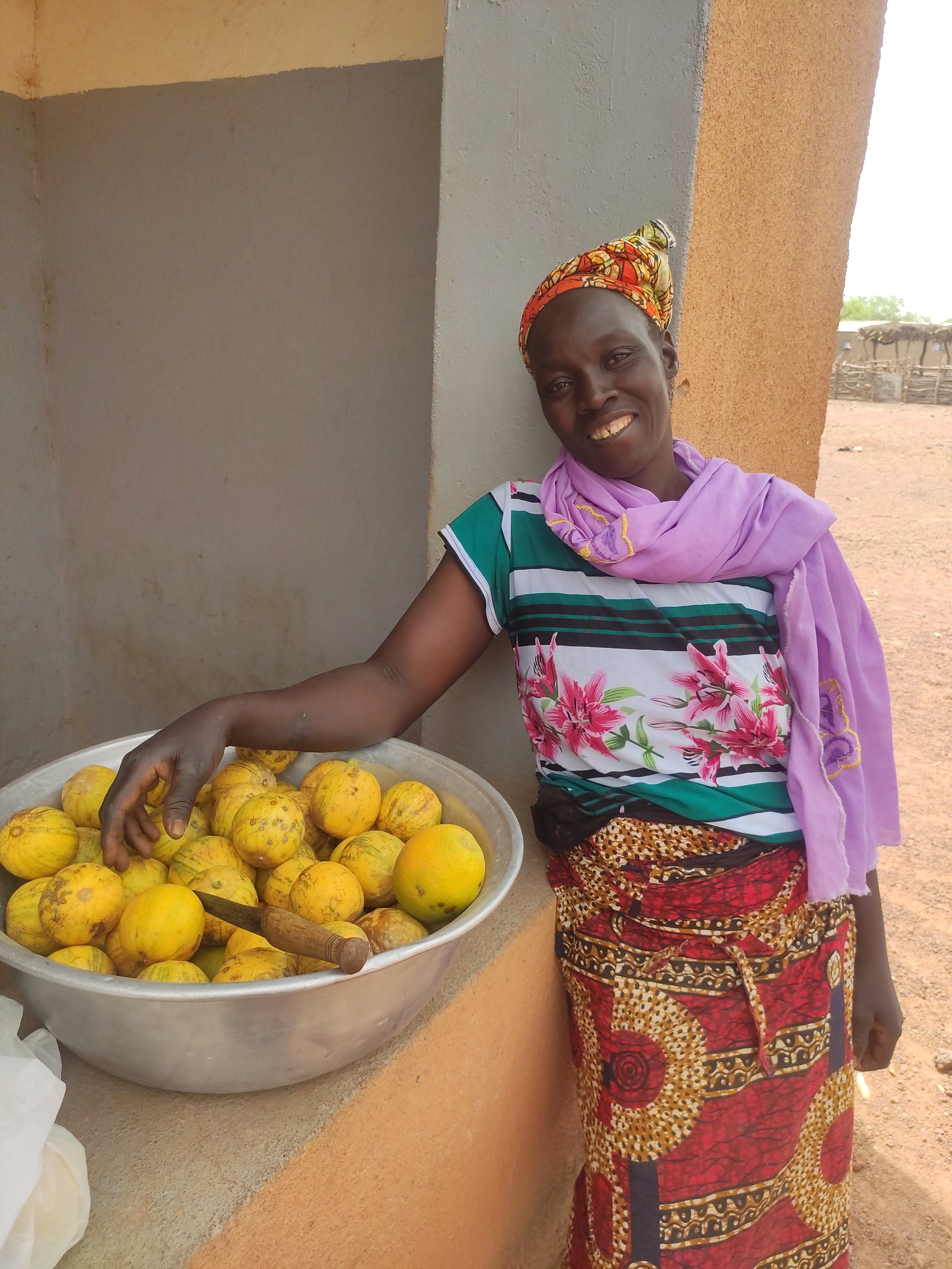 Bintou shows of the fruit she imports using her Mothers' Loan Fund capital.