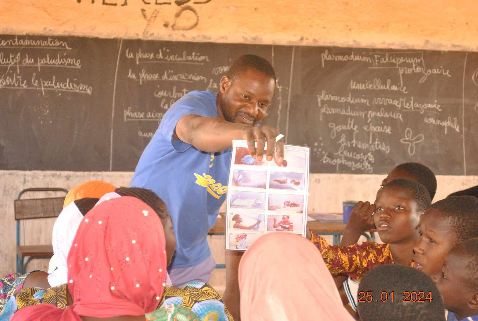 The health worker explains malaria prevention to students.