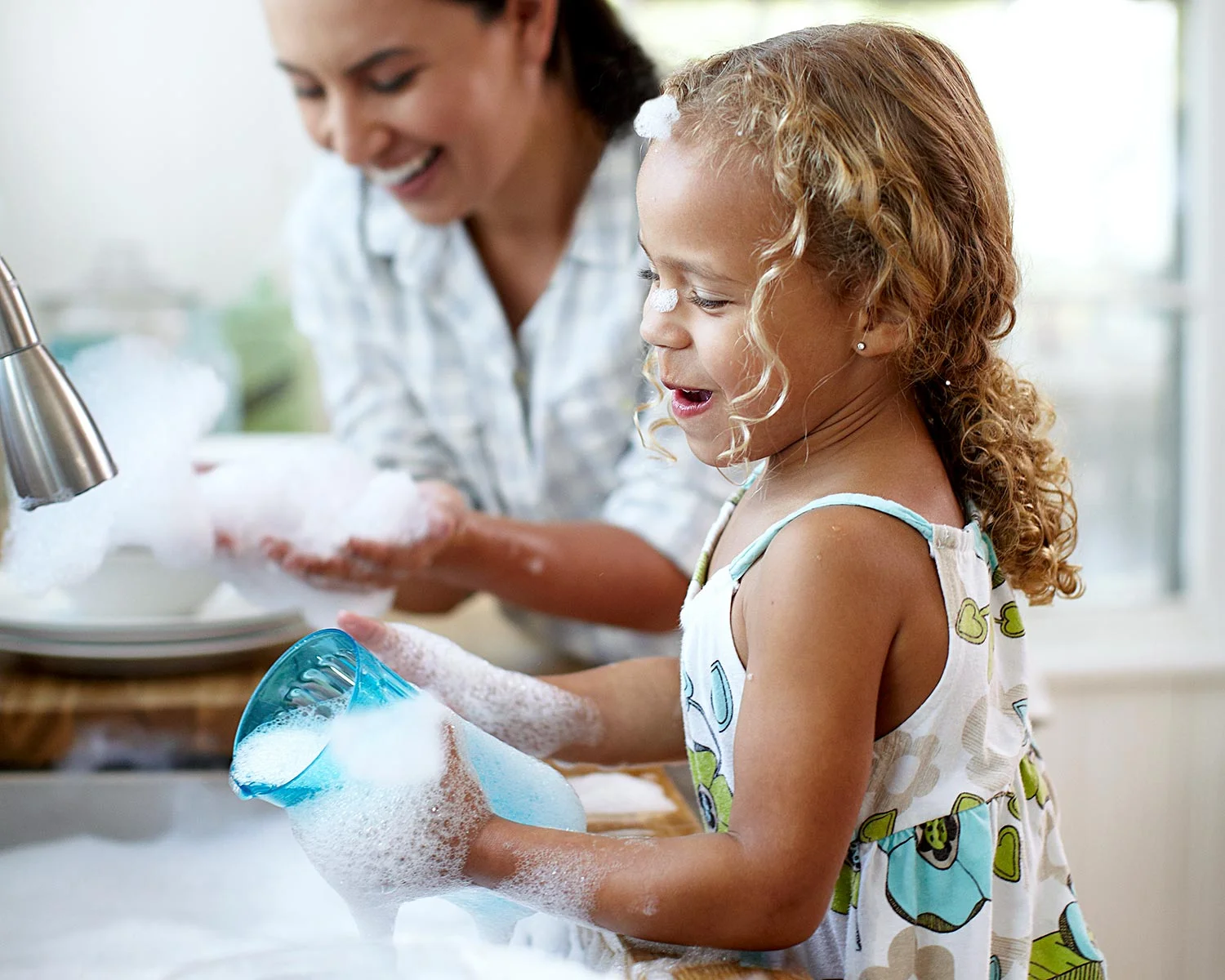 Mother and daughter having fun washing dishes with Legacy dish soap.
