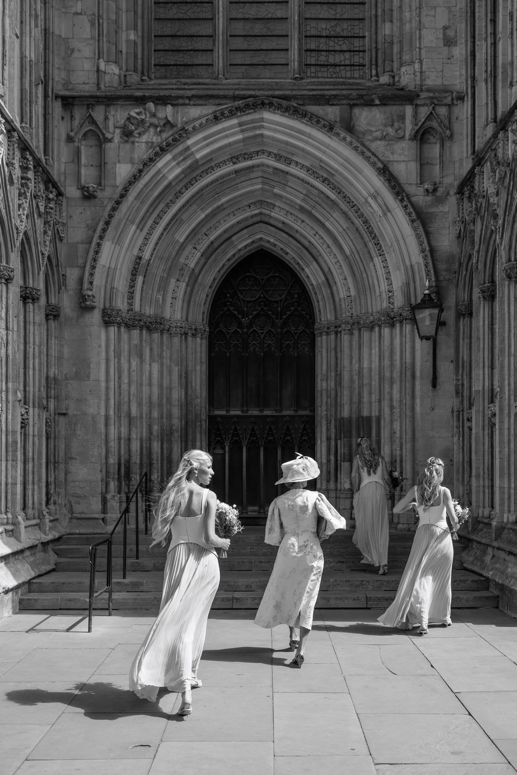 Bride and bridesmaids walking towards the entrance of York Minster on a wedding day