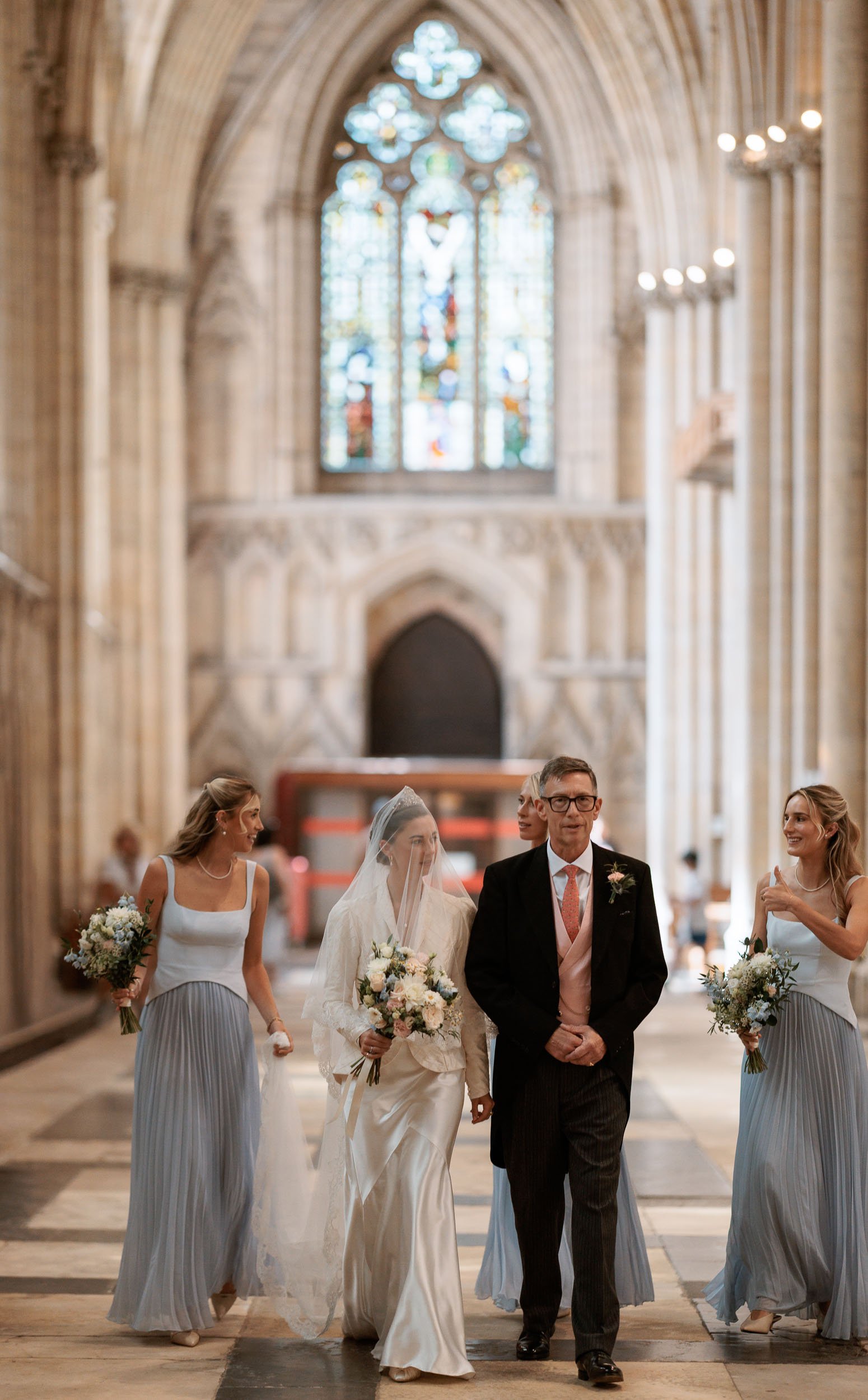 A bridal party walks through the caverned halls of York Minster.