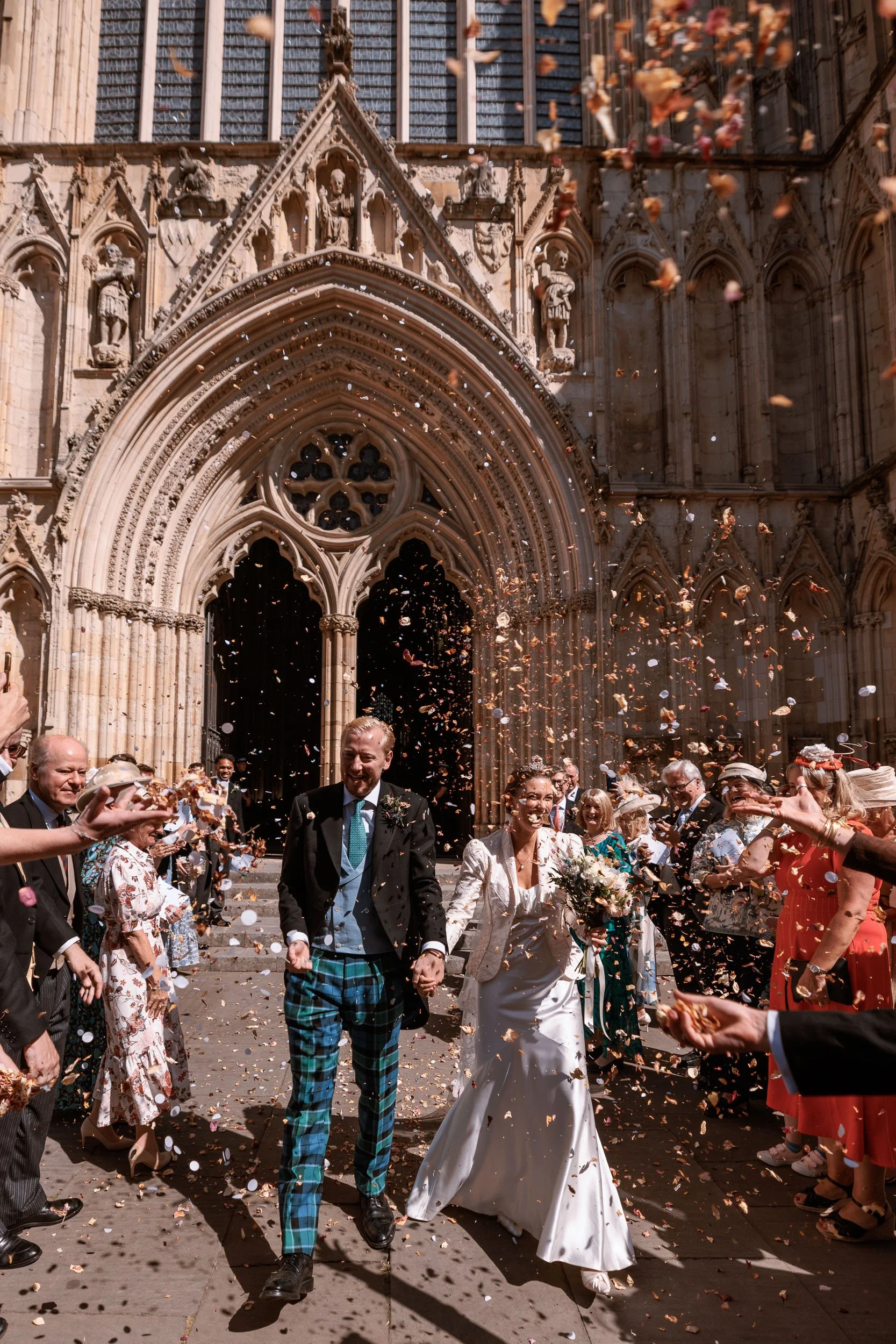 Alicia and Max surrounded by confetti and wedding guests after their York Minster ceremony.