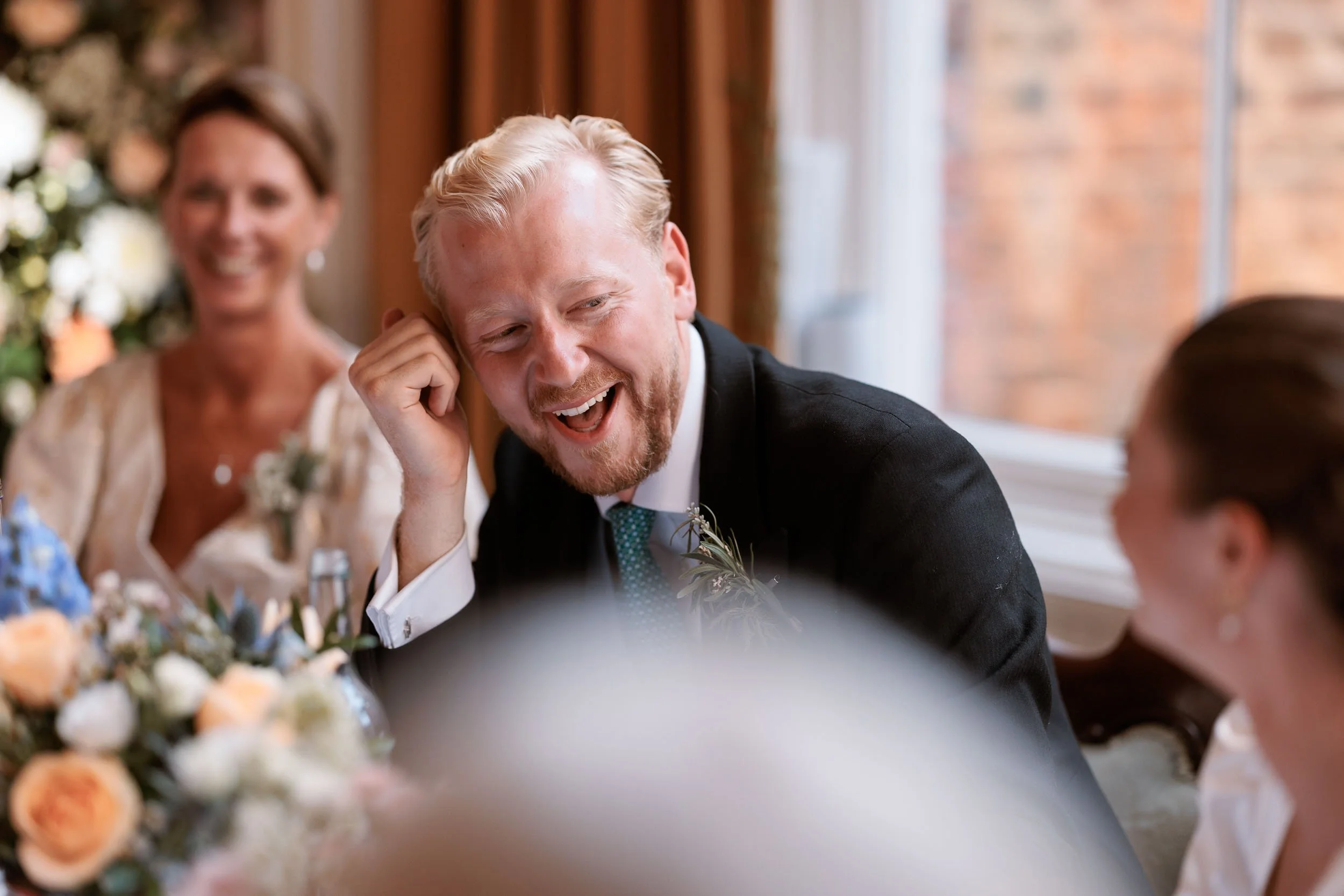 Alicia and Max laughing together during the wedding speeches.