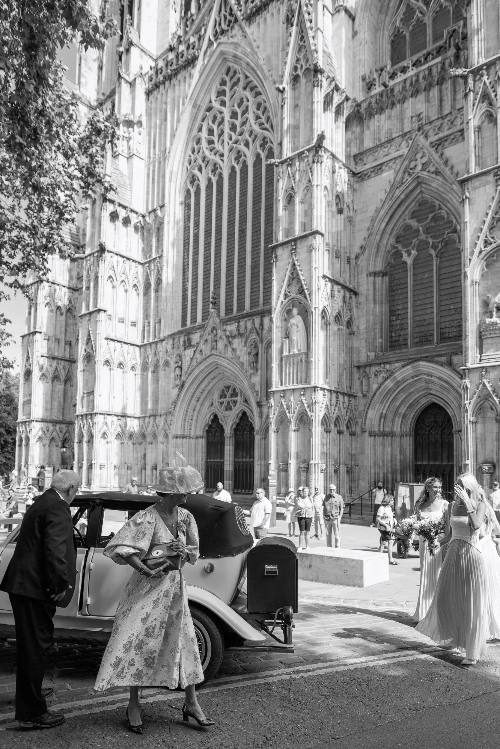 Mother of the bride stepping from the vintage wedding car with the entrance to York Minster behind her.