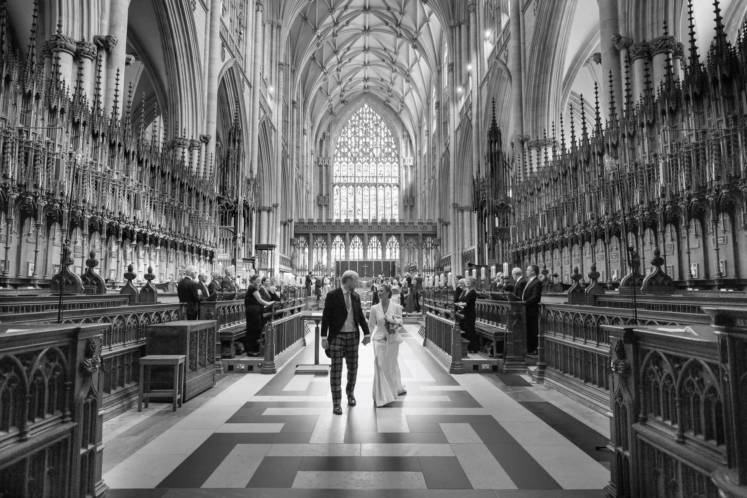 Bride and groom walking through the nave of York Minster after their wedding ceremony