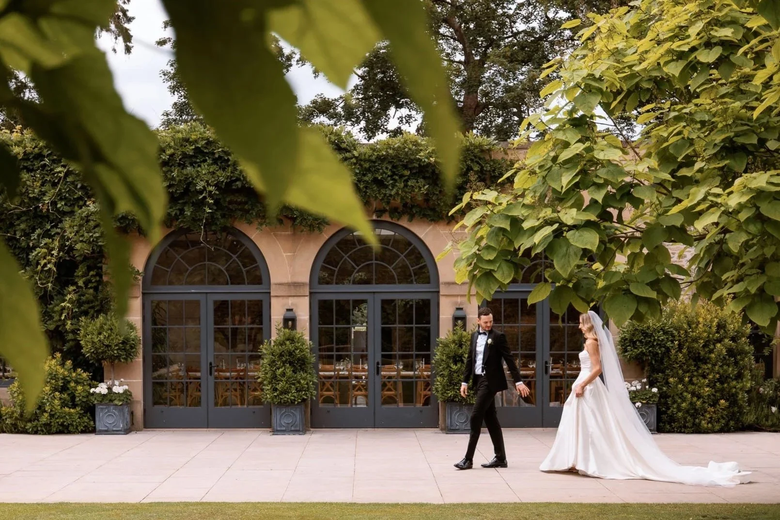 Newlyweds crossing the lawn beside the Fig House at Middleton Lodge.