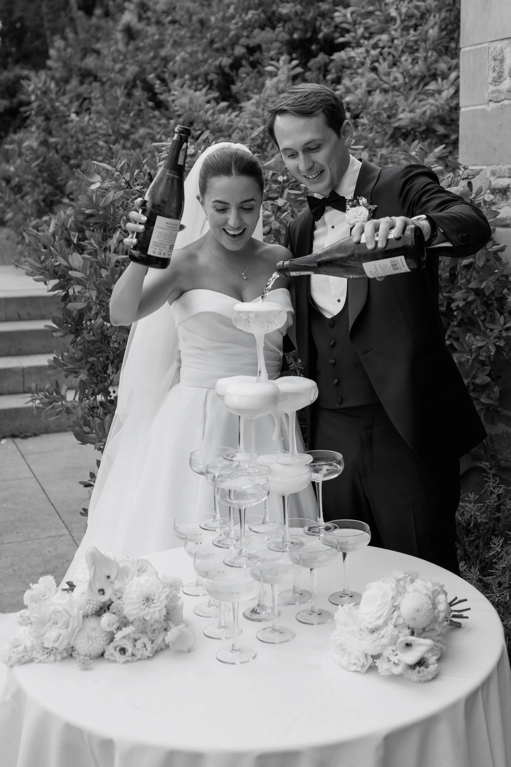 Black and white photograph of newlyweds and their champagne tower.