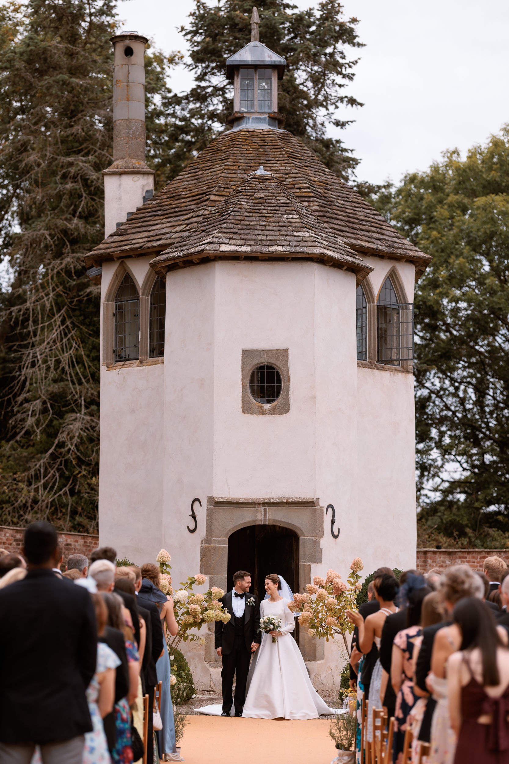 Outdoor wedding ceremony in the Walled Garden at Homme House, Herefordshire, with guests seated in front of the historic 17th-century Summerhouse.