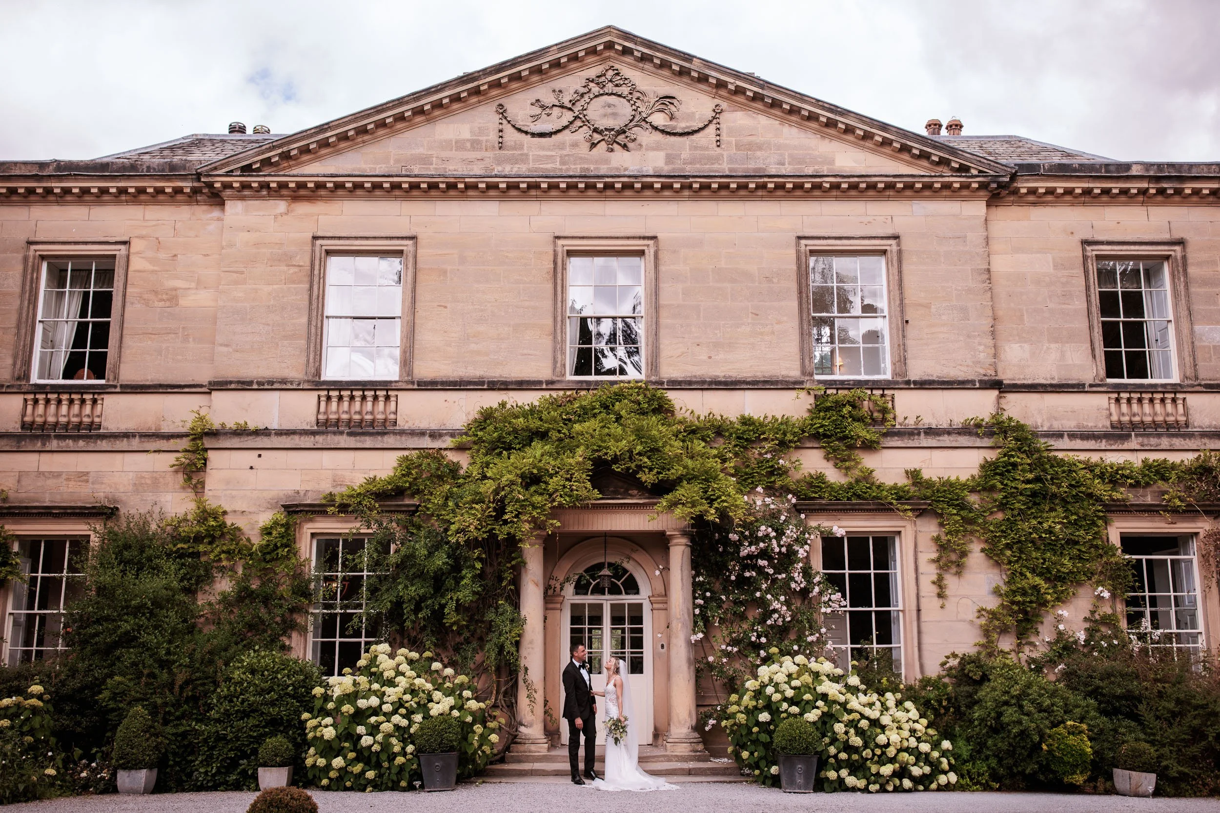 Newlyweds at the front entrance of Middleton Lodge Main House in North Yorkshire.
