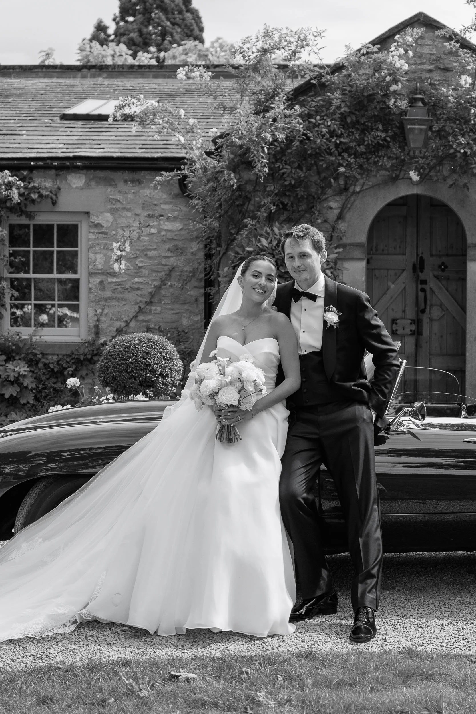 Emily and Lewis leaning against a classic Jaguar E-Type outside the Fig House at Middleton Lodge, North Yorkshire.
