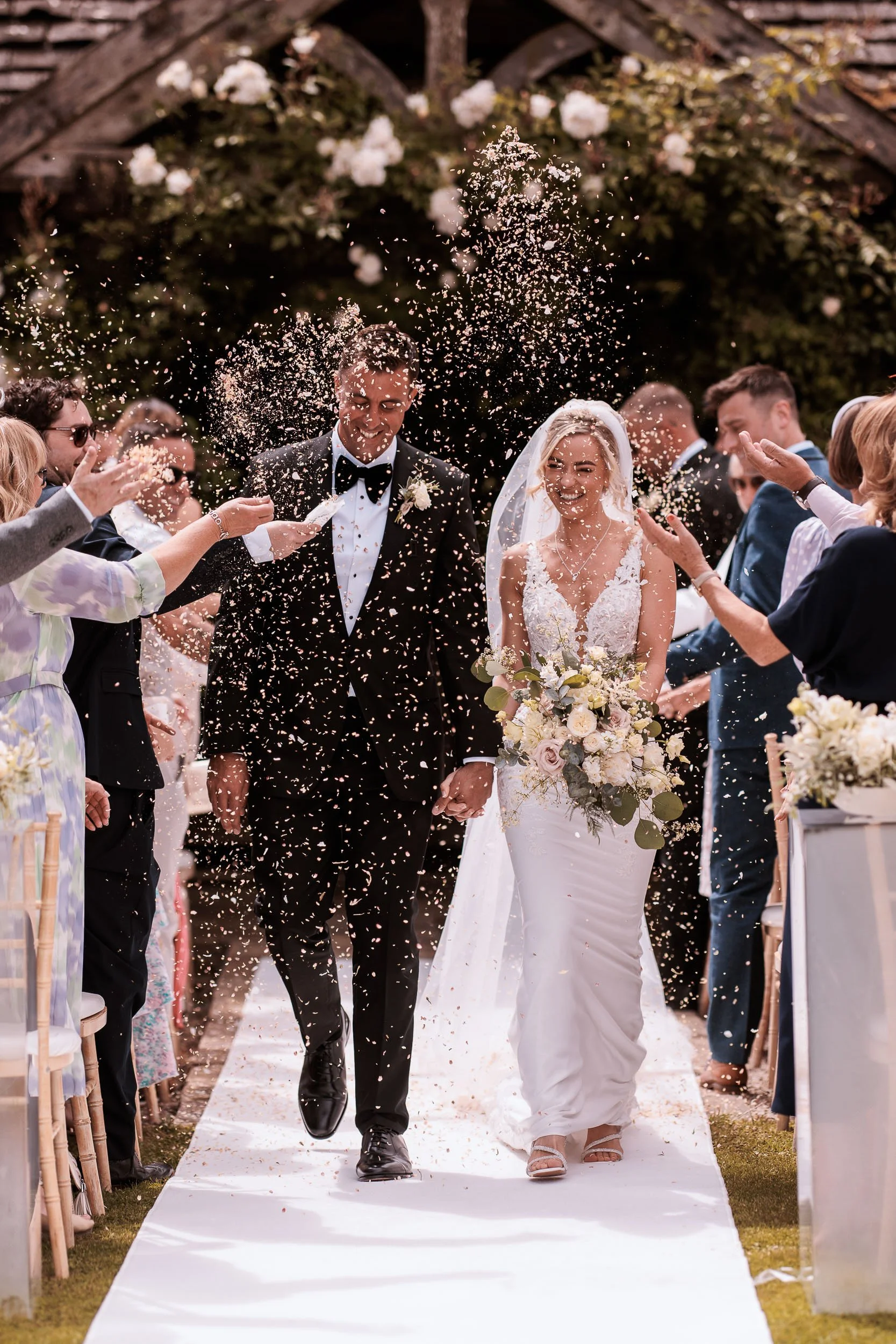 Newlyweds walking through confetti after their ceremony at Middleton Lodge.