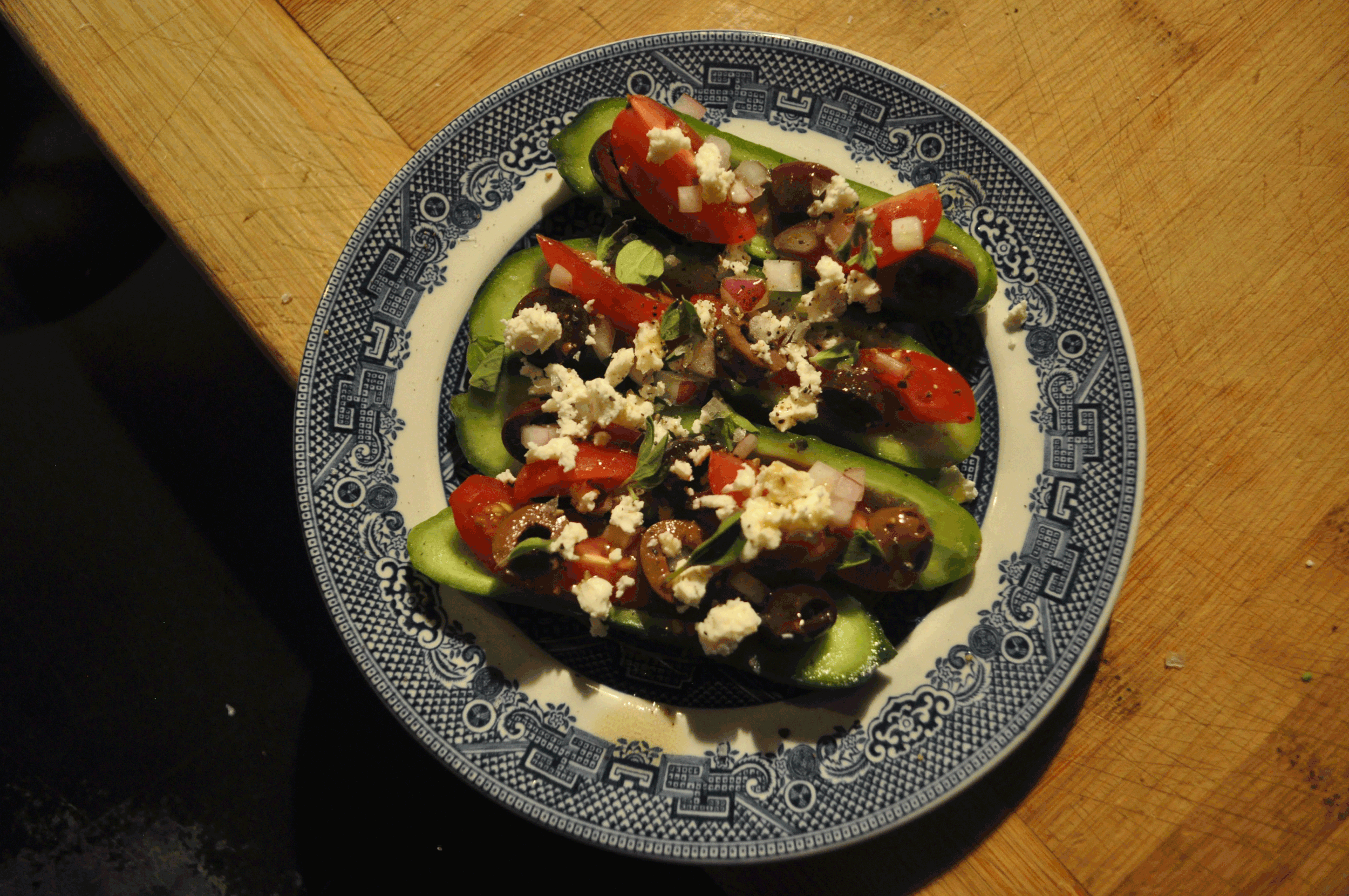 greek salad in romaine lettuce cups on a blue and white plate