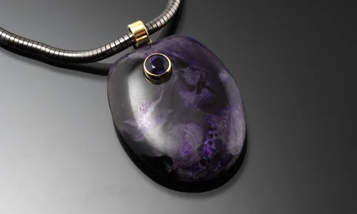   Free form stone pendant in 18K yellow gold. Sugilite with 4.5mm faceted amethyst accent. Width 1" Length 1.25" Depth 0.25"     