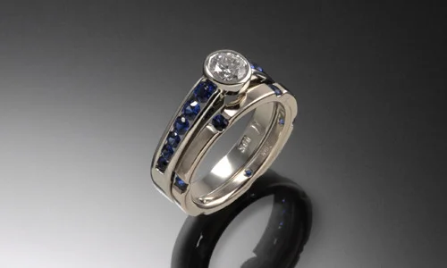   Engagement ring and wedding band set in 18K white gold, blue sapphires and center diamond. Each approximate width 0.15"﻿  
