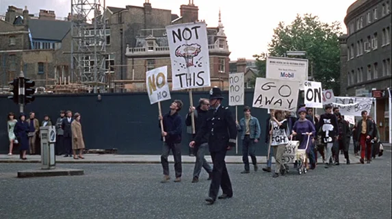 Blow-Up The protest march near the beginning of the film that is juxtaposed with the mimes and Thomas driving his Rolls Royce through London - he accepts the offering of the "no" sign as a token but immediately looses it.