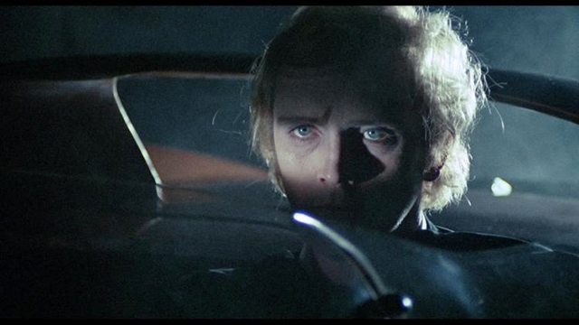 Toby Dammit Great lighting focuses on the eyes as a subtle triangle of orange - the color most prominent from the airport scene - points to the face of Toby looking doomed while pinned inside his car by the narrow windshield in the front and the roll bar in the back.