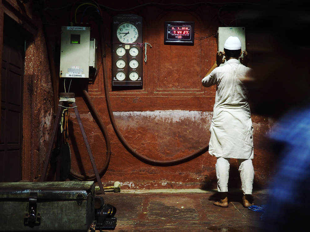 Guarding the entrance of the Jama Masjid, a man prays after breaking fast.