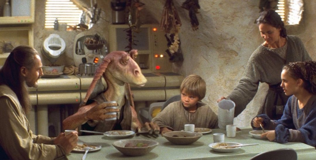 Young Anakanin Skywalker sits down to eat with Queen Amidala and Qui‑Gon Jinn, in Star Wars: Episode I – The Phantom Menace.