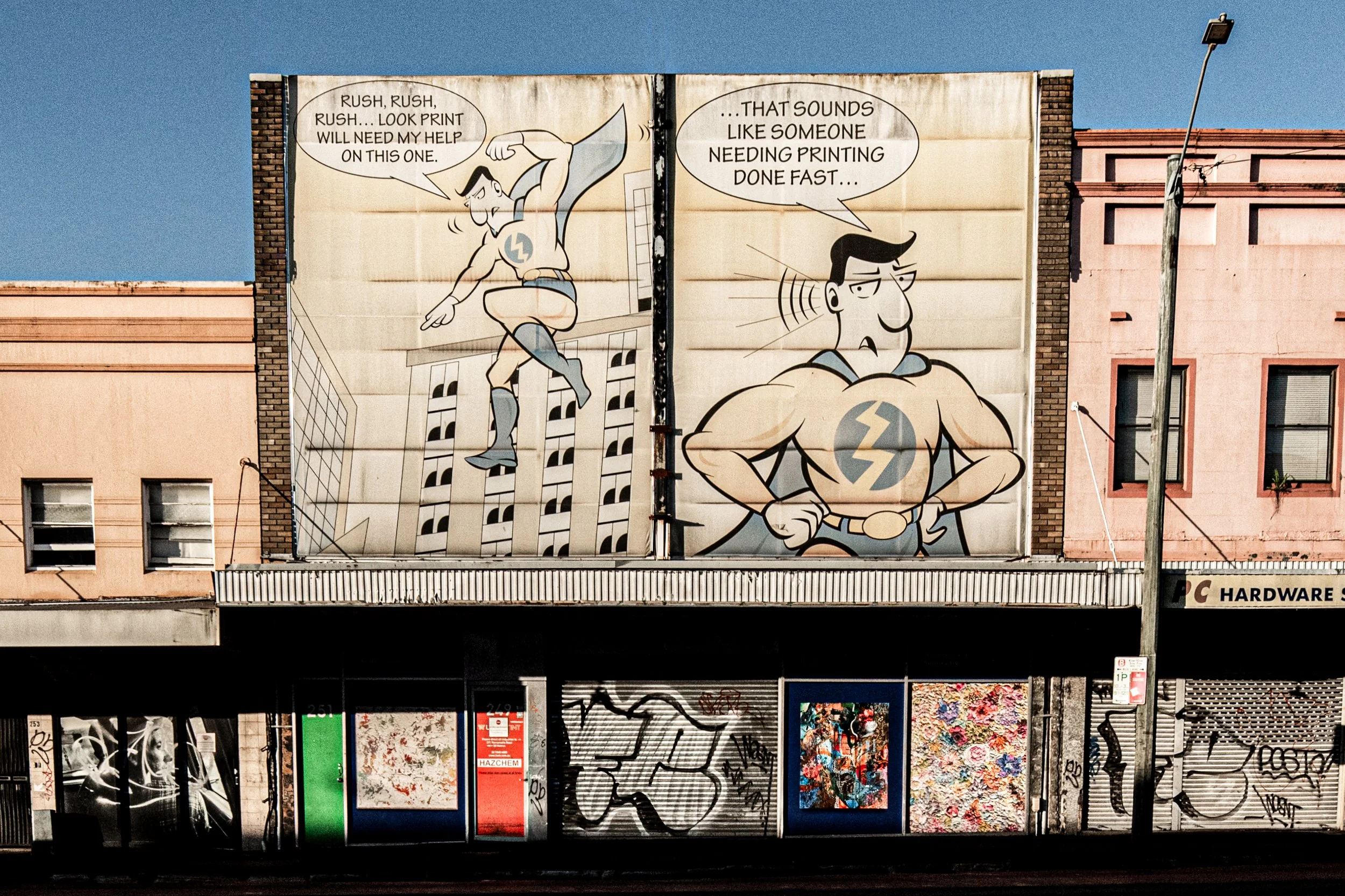  249-251 Parramatta Road, Annandale  The large comic-style mural was added by Look Group, a signage and print business. Behind it is an early 20th-century shop-house, aligned in height and proportion with the Victorian and Federation buildings beside