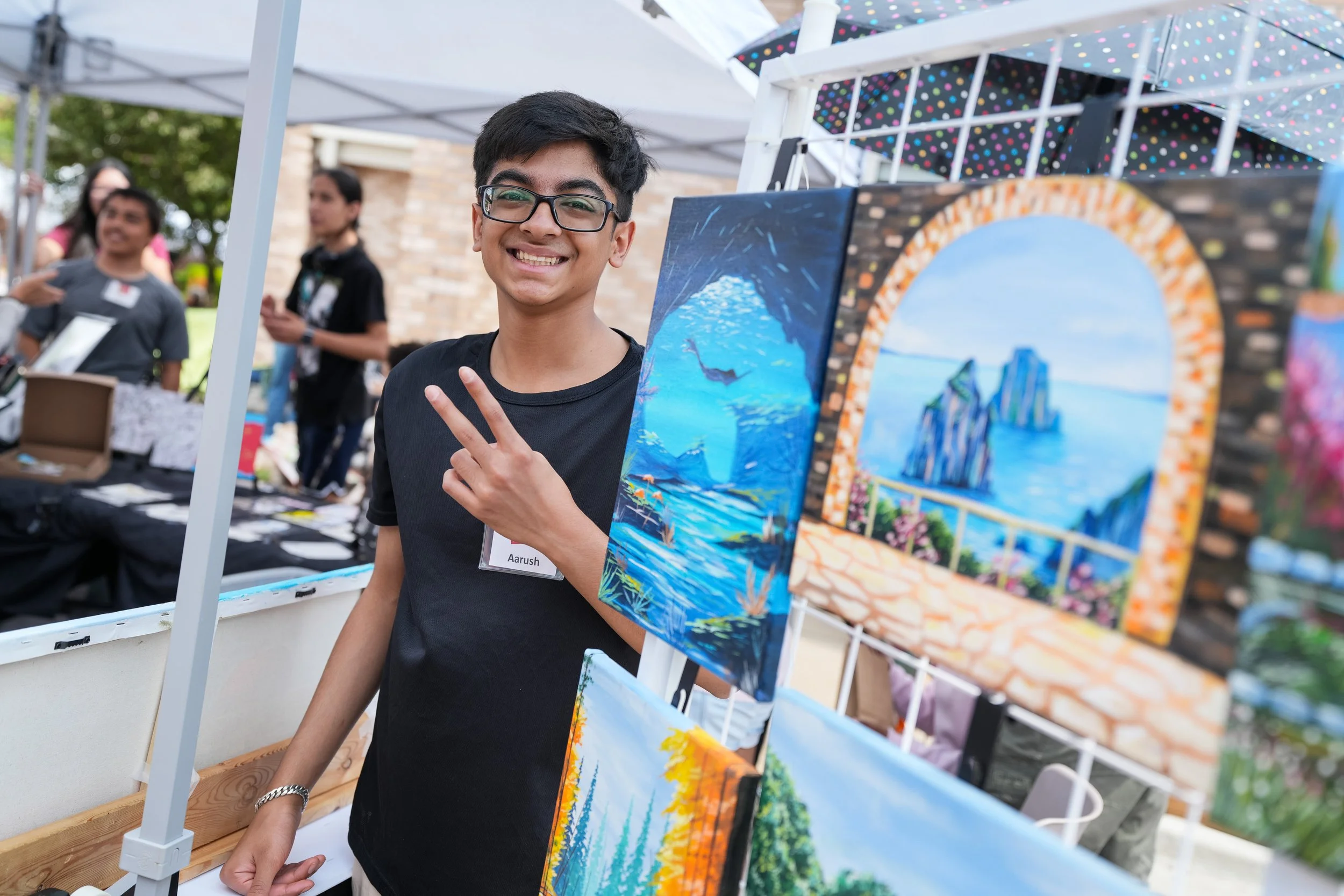 KAA - Aarush giving peace sign with paintings.jpg