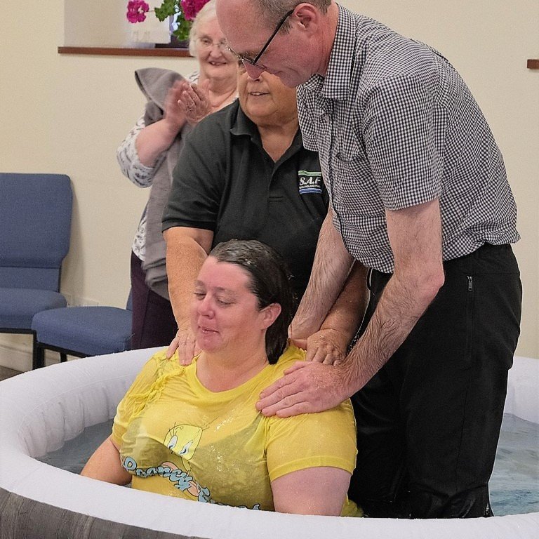  A woman sitting in an inflatable pool being baptised by two leaders at Stoke Baptist Church in September 2022.  READ MORE . 